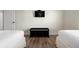 The image shows the foot of two twin beds, wood floors, and a black bench with a TV mounted on the wall at 215 65Th St, Holmes Beach, FL 34217