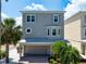 Charming three-story home with gray siding, a covered porch, and a well-maintained lawn and tropical landscaping at 215 65Th St, Holmes Beach, FL 34217