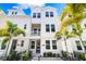 Charming three-story townhome with white siding, balcony, and lush tropical landscaping at 2408 Ezzell Ct, Sarasota, FL 34237
