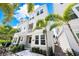 Low angle of a three-story townhome with white siding and tropical landscaping at 2408 Ezzell Ct, Sarasota, FL 34237