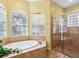This primary bathroom features a large soaking tub, a stand-alone shower and bright windows at 2496 Farms Ct, Sarasota, FL 34240
