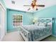 Light blue bedroom featuring a queen-sized bed with floral bedding and a ceiling fan at 2496 Farms Ct, Sarasota, FL 34240