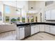 Well-lit kitchen with granite countertops, white cabinets, and an open view to the living room and outdoor scenery at 2496 Farms Ct, Sarasota, FL 34240