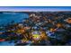 Stunning aerial view of a waterfront home at twilight showcasing the pool, lighted grounds, and coastal skyline at 26 Sandy Hook S Rd, Sarasota, FL 34242