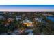 Aerial night view of a luxury home with a pool and beautifully lit landscaping at 26 Sandy Hook S Rd, Sarasota, FL 34242