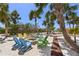 Relaxing beach firepit with colorful Adirondack chairs surrounded by palm trees on a sunny day at 26 Sandy Hook S Rd, Sarasota, FL 34242
