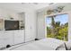 Cozy bedroom with built-in storage, bright windows and serene views of lush tropical landscaping at 26 Sandy Hook S Rd, Sarasota, FL 34242