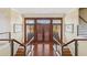 Grand entryway with glass-railed staircases, dark wood doors, and bright lighting creating a welcoming entrance at 26 Sandy Hook S Rd, Sarasota, FL 34242