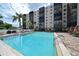 Resort-style pool with lounge chairs and tables against the backdrop of a condo building and tropical palm trees at 2901 26Th W St # 312, Bradenton, FL 34205