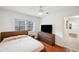 This naturally lit bedroom is simple with a window, television, and wood floors at 3006 Wister Cir, Valrico, FL 33596