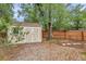 A backyard shed in a wooded yard surrounded by a wood fence and stone pathway at 3006 Wister Cir, Valrico, FL 33596