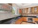 View of a well-lit kitchen featuring modern appliances, warm wood cabinetry and black countertops at 33 Bishops Court Rd # 118, Osprey, FL 34229