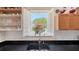 Bright kitchen sink with black countertop, and an open window with white shutters at 33 Bishops Court Rd # 118, Osprey, FL 34229