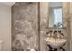 Stylish powder room featuring stone walls, a unique stone vessel sink, and modern fixtures at 33 Bishops Court Rd # 118, Osprey, FL 34229