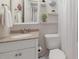 A cozy bathroom featuring neutral walls, decorative shelving, and a vanity with a granite countertop at 3320 Gulf Of Mexico Dr # 307C, Longboat Key, FL 34228