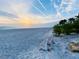 Serene beach view with a bench for relaxation, offering a tranquil coastal experience at sunset at 3320 Gulf Of Mexico Dr # 307C, Longboat Key, FL 34228