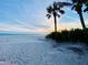 A serene beach view with palm trees and the ocean at sunset, offering relaxation at 3320 Gulf Of Mexico Dr # 307C, Longboat Key, FL 34228