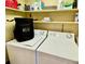 A compact laundry room with a washer, dryer, storage shelves, and essential cleaning supplies at 3320 Gulf Of Mexico Dr # 307C, Longboat Key, FL 34228
