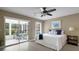 Bright bedroom featuring a ceiling fan, view to a sunroom, and a comfortable bed with stylish decor at 3666 Bonaventure Ct, Sarasota, FL 34243