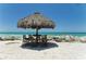 Secluded dining area with a thatched umbrella and seating offers privacy on a serene beach at 3740 Lake Bayshore Dr # Bldg K, Bradenton, FL 34205