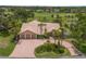 Stunning aerial view of a home featuring a three-car garage, circular driveway, and lush landscaping, all backing onto a golf course at 3936 Spyglass Hill Rd, Sarasota, FL 34238