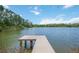 Scenic waterfront view with a wooden dock extending into the lake surrounded by lush greenery and a blue sky at 4225 Ulman Ave, North Port, FL 34286