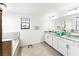 Bathroom featuring a soaking tub, double vanity with granite counters, tile flooring, and modern fixtures at 5333 Coral Reef Way, Bradenton, FL 34211