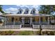 Charming yellow home with a welcoming front porch, American flags, and well-manicured landscaping at 553 Meadow Sweet Cir, Osprey, FL 34229