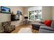 Sunlit living room featuring a modern desk, television, comfortable seating, and a large window overlooking the yard at 553 Meadow Sweet Cir, Osprey, FL 34229