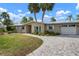 Charming single-story home featuring a brick driveway, a two-car garage, and mature landscaping at 602 Baronet Ln, Holmes Beach, FL 34217