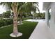 Backyard with synthetic grass, palm trees and walkway leading to the pool and outdoor living areas at 603 Emerald Ln, Holmes Beach, FL 34217