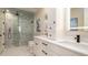 This bathroom has dual sinks, white cabinets, a modern lighting fixture, and a marbled glass-door shower at 603 Emerald Ln, Holmes Beach, FL 34217