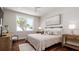 Comfortable bedroom with neutral colors, wood floors, decorative nightstands and a large sun-filled window at 603 Emerald Ln, Holmes Beach, FL 34217