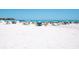 Picturesque beach scene with soft white sand, blue umbrellas, and relaxing beachgoers enjoying the sun at 6512 Midnight Pass Rd # 303, Sarasota, FL 34242