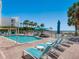 Community pool area with lounge chairs and umbrellas steps away from a sandy beach at 6512 Midnight Pass Rd # 303, Sarasota, FL 34242