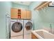 This functional laundry room features a washer, dryer, sink, and storage cabinets for efficient and organized laundry tasks at 6539 Flycatcher Ln, Lakewood Ranch, FL 34202