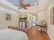 This primary bedroom features a ceiling fan, TV, wood floors, and a walk-in bathroom for maximum comfort and convenience at 6539 Flycatcher Ln, Lakewood Ranch, FL 34202
