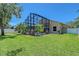 A screened-in pool is surrounded by tropical landscaping and a lush green lawn in this home's backyard at 6605 38Th E Ln, Sarasota, FL 34243
