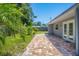 A paved patio and lush green lawn with tropical foliage defines this home's inviting backyard at 6931 Magellan Way, Sarasota, FL 34243