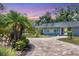 Charming home showcasing a stone driveway and meticulous landscaping with palm trees at 6931 Magellan Way, Sarasota, FL 34243