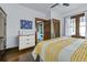 Bright bedroom with dark wood floors, white walls, a wooden dresser and a stylish yellow bed spread at 720 37Th W St, Bradenton, FL 34205