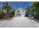 Charming two-story home with a white gravel driveway, lush landscaping, and a light gray facade at 799 Jacaranda Rd, Anna Maria, FL 34216