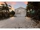 Charming two-story home with white exterior, double garage, palm trees, and a balcony, offering curb appeal at 799 Jacaranda Rd, Anna Maria, FL 34216