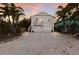 Charming two-story home with white exterior, double garage, palm trees, and a balcony, offering curb appeal at 799 Jacaranda Rd, Anna Maria, FL 34216