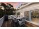 Outdoor deck with a dining area, grill, and lush tropical surroundings, with a peek into the living room at 799 Jacaranda Rd, Anna Maria, FL 34216