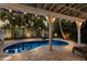 A serene backyard pool surrounded by lush tropical foliage and an inviting brick patio for outdoor relaxation at 799 Jacaranda Rd, Anna Maria, FL 34216