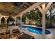 Relaxing backyard pool area with lounge chairs, tropical foliage, and a charming covered patio space at 799 Jacaranda Rd, Anna Maria, FL 34216