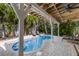Backyard pool and patio area shaded by a pergola and surrounded by palm trees at 799 Jacaranda Rd, Anna Maria, FL 34216