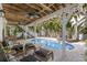 Backyard pool area with comfortable seating, lush landscaping, and a shaded pergola at 799 Jacaranda Rd, Anna Maria, FL 34216