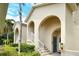 Close-up of a beige condo building entrance showcasing arched entryways, white railings, and verdant landscaping at 8315 Glenrose Way # 1421, Sarasota, FL 34238